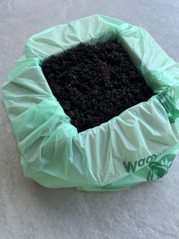 Picture containing an open box displaying 1L of Wiggly Castings (worm castings) also known as black gold.